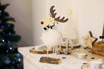 Christmas composition with beautiful decoration, christmas tree and wooden deer, horse, stars and other accessories in modern home.