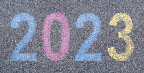 Start the New year 2023 stenciled in pavement paint on the asphalt, start trip concept. Celebration...