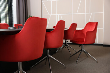 Stylish red office chairs and large table in empty conference room