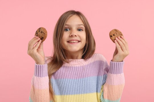 Cute girl with chocolate chip cookies on pink background