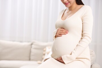 Pregnant woman at home, closeup. Space for text