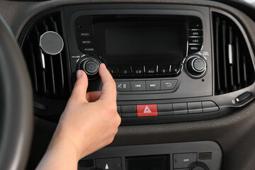 Listening to radio while driving. Woman turning volume button on vehicle audio in car, closeup - obrazy, fototapety, plakaty