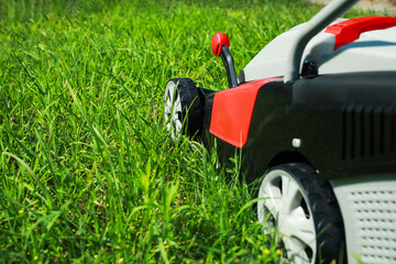 Lawn mower on green grass in garden, space for text