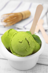 Tasty matcha ice cream in bowl on white wooden table