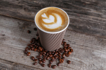 Coffee to go. Paper cup with tasty drink and roasted beans on wooden table