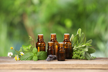 Bottles with essential oils and plants on wooden table against blurred green background. Space for...