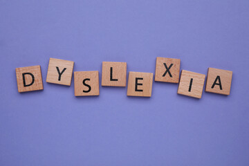 Wooden cubes with word Dyslexia on violet background, flat lay