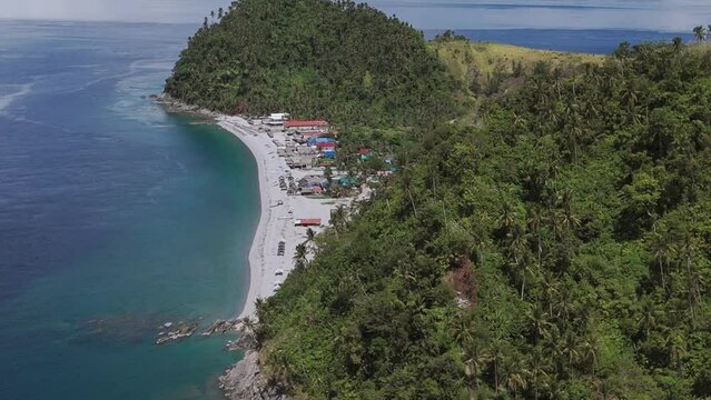 Looc Beach in Surigao, Philippines, on a bright clear day with turquoise waters and lush jungle hills. Aerial drone shot. 