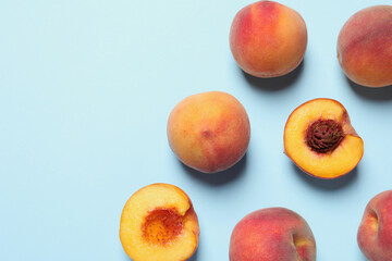 Cut and whole fresh ripe peaches on light blue background, flat lay. Space for text