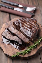 Delicious grilled beef meat and rosemary served on wooden table, closeup