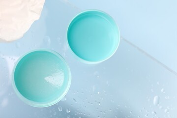 Lip balm and water drops on glass surface, flat lay