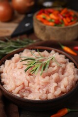 Fresh raw minced meat and rosemary in bowl on table, closeup