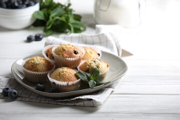 Delicious sweet muffins with blueberries and mint on white wooden table. Space for text