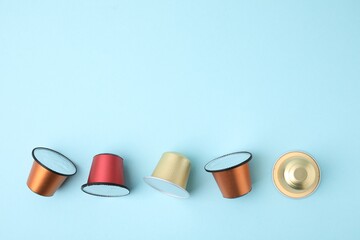 Many coffee capsules on light blue background, flat lay. Space for text