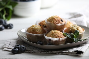Delicious sweet muffins with blueberries and mint on white wooden table, closeup