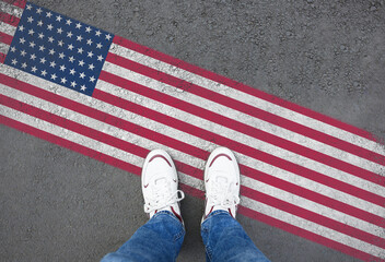 Immigration. Man standing on asphalt near flag of USA, top view