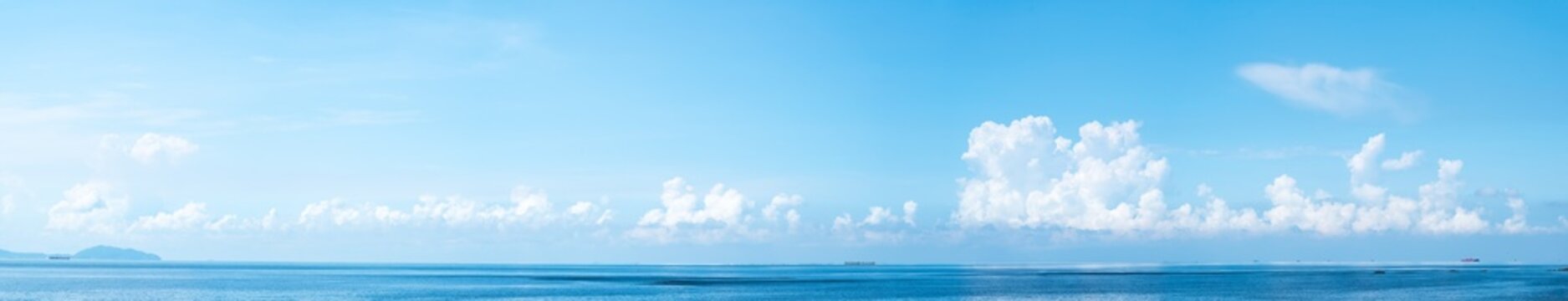 Panoramic blue sky with white fluffy clouds and sea