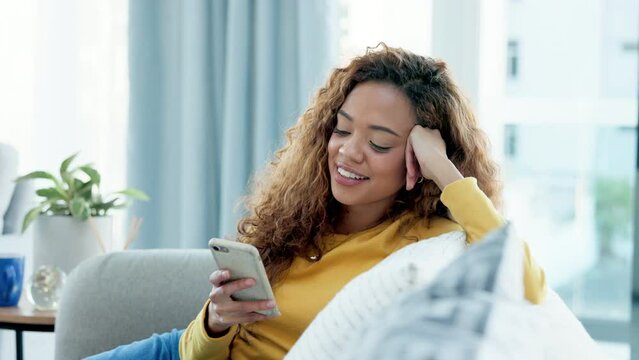 Trendy girl laughing, watching videos on her phone and texting. Entertained young woman watching funny series, movies or shorts on social media and surfing the internet while enjoying her weekend