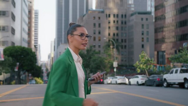 Caucasian businesswoman in suit using smartphone on city street in downtown. Smiling stylish beautiful lady in eye fashion glasses miles looks successful. Trendy female browsing on web using device 4K