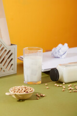 Concept of office desk with glass cup and bottle filled with soy milk. Soybeans contained in a...