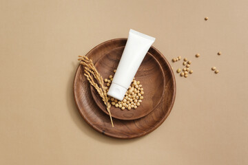 A tube without label placed on wooden dishes with soybeans. Soybean (Glycine max) benefits include...