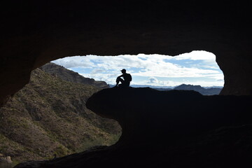 Silhouette of a hiker sitting in the Wave Cave in Gold Canyon, Arizona.