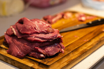 a photograph with raw meat cut into steaks to make cordovan tenderloins with a knife and a close-up of a hand cleaning or tenderizing the meat