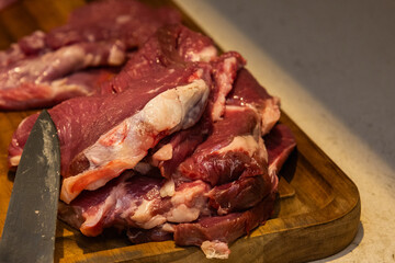 a photograph with raw meat cut into steaks to make cordovan tenderloins with a knife and a close-up of a hand cleaning or tenderizing the meat