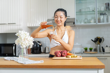 A healthy Asian woman in exercise clothes Is happily cooking a healthy meal in her home kitchen in...