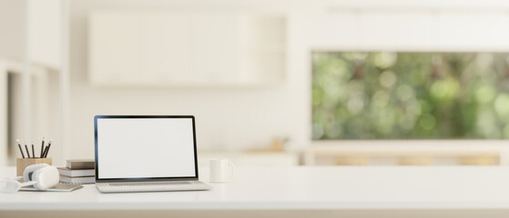 A white-screen laptop mockup on a white tabletop with a blurred background of a modern white room.