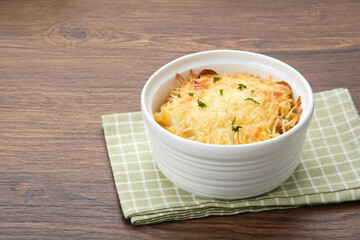 Baked macaroni and cheese on a white bowl with parmesan and herbs
