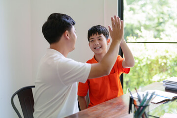 Father and son giving high five together after doing homework finished with happiness family moment