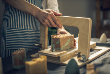 Cutting of homemade natural soap on a professional wood cutter. A means of eco-friendly hygiene and pleasant gifts