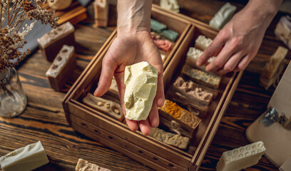 A woman soap maker holds a piece of chocolate soap in her hands. Lots of different sliced pieces. Eco-friendly natural handmade cosmetics