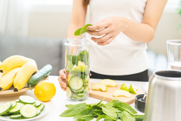 Vegetable smoothie detox, woman hand making healthy raw fresh green fruit juice with blender machine, preparing drink with spinach in kitchen at home, eating vegan diet. Healthy dieting, weight loss.