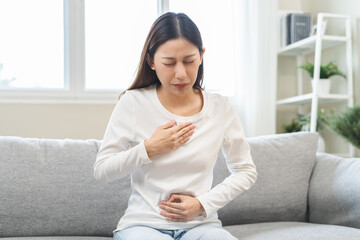 Acid reflux disease, suffer asian young woman have symptom gastroesophageal, esophageal, stomach ache and heartburn pain hand on chest from digestion problem after eat food, Healthcare medical concept - obrazy, fototapety, plakaty