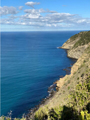 Atop the mountain, witness the breathtaking union where the beautiful blue ocean embraces the vast expanse of the sky, a seamless horizon painting a panoramic masterpiece.