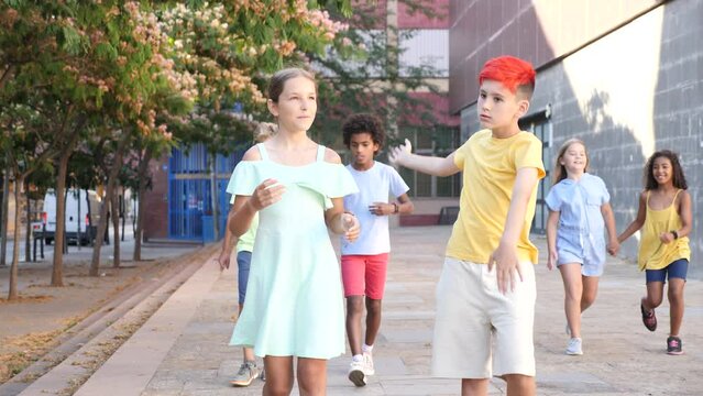 Happy carefree tweens girl and boy enjoying friendly conversation while walking down city street during summer vacation. High quality 4k footage