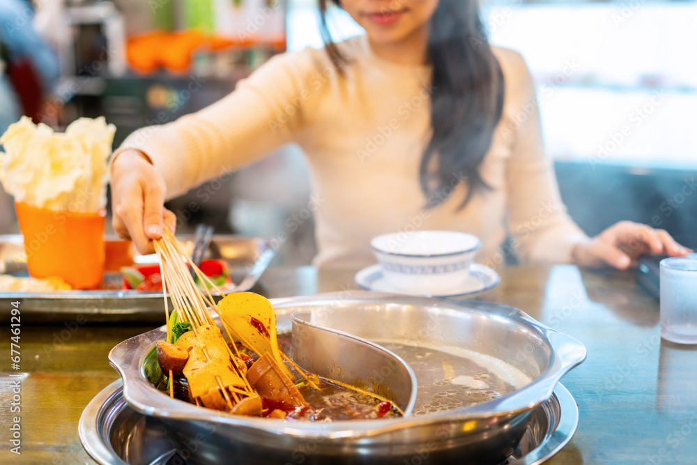 Wall mural Female tourist eating original mala spicy hot pot (Chuan Chuan) at restaurant in Chengdu, China