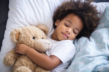 Toddler boy with dark hair in shirt sleeps sweetly in company of best friend teddy bear seeing pleasant dreams. Little boy has sweet dreams in bed with favorite toy small teddy bear