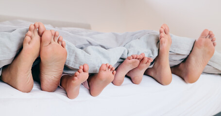 Family, feet and sleeping in bed, morning or relax together with kids and parents under blanket....