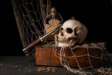 Pirate chest with spyglass, human skull, bottle of rum and coins on black background