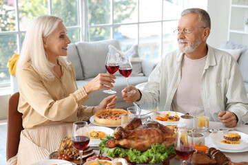 Mature couple having dinner at festive table on Thanksgiving Day