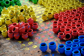 Obraz premium 07 November 2023, Pune, India, An Potter applies colour to earthenware oil pots or diyas at a workshop, ahead of the forthcoming Diwali festival, the Hindu festival of lights.