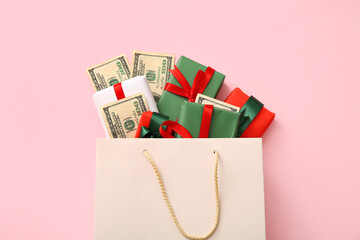 Shopping bag with Christmas gift boxes and money on pink background