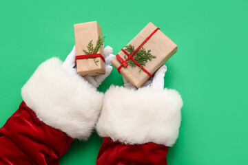 Santa Claus with gift boxes and coniferous branches on green background