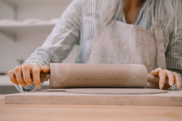 Female hands working with clay makes ceramic tableware on pottery workshop.