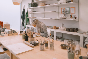 Woman creating clay product on ceramics workshop in art studio. Craftsperson on pottery workshop.