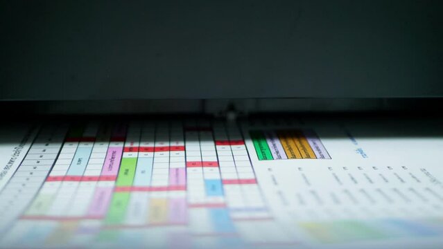 Black inkjet printer printing tabular information on white paper in color.
