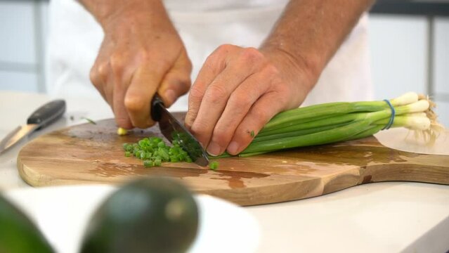 Slicing scallions on cutting board to use as garnish for zoodle dish
